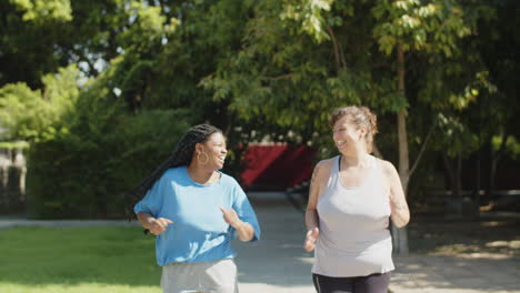 Front-view-of-smiling-women-running-along-path-in-public-park