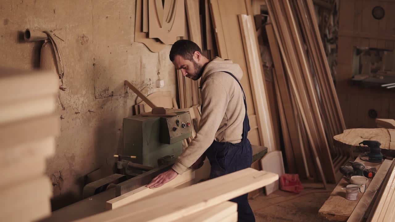 vista lateral de un artesano trabajando en una sierra eléctrica con madera. empuja el bloque de madera con las manos