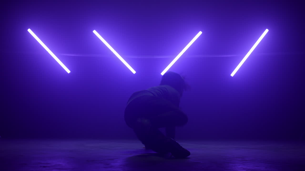 un hombre bailando hip-hop bajo luces ultravioletas, un joven b-boy con un cuerpo giratorio.