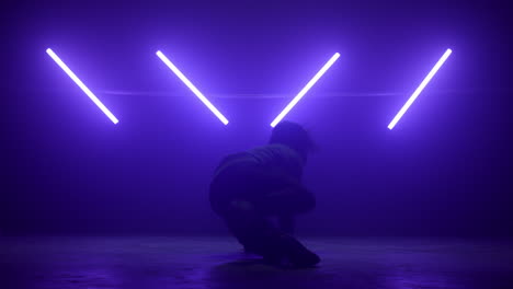 man dancer performing hip-hop in ultraviolet lights. young b-boy spinning body.