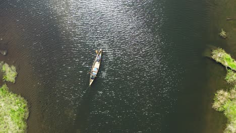 Top-down-drone-shot-of-two-people-paddling-a-canoe-in-an-estuary
