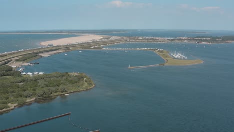 Drone---Aerial-shot-of-surfer-and-sailing-boats-on-a-blue,-wavy-and-windy-sea-on-a-sunny-day-with-white-clouds-on-a-island,-30p