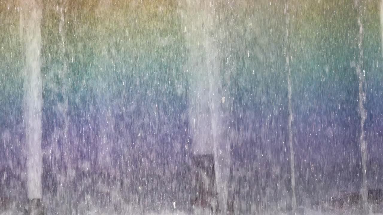 Close-up view of colorful rainbow patterns forming in the mist of a fountain.