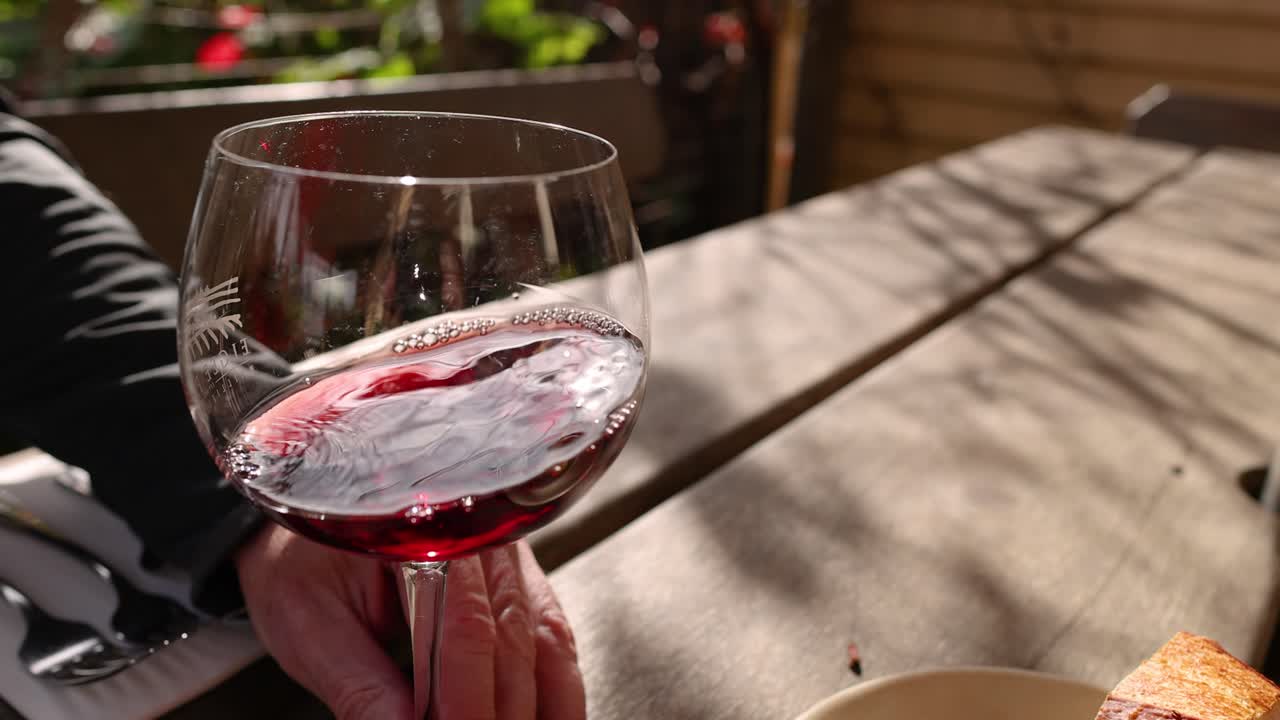 Hand swirling red wine in a glass
