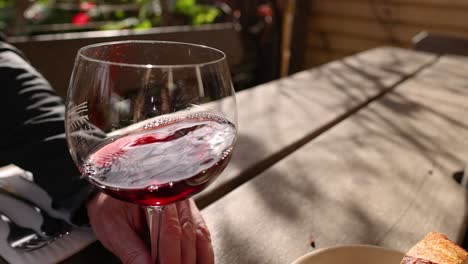 hand swirling red wine in a glass