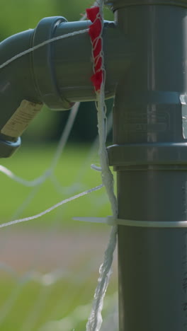 a close-up of a soccer ball hitting the goalpost net as the blurred goalkeeper tries to save the ball with his right hand after it has entered the goal post