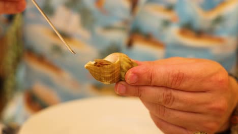 person extracting clam meat with a toothpick