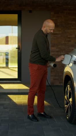man charging electric vehicle at home