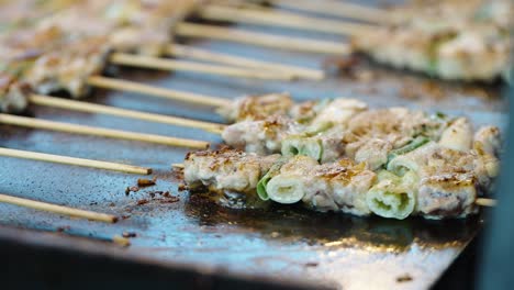 meat and vegetable skewers cooking at food stall, japanese summer festival