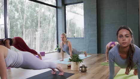 Mujeres-Jóvenes-Multirraciales-Practicando-Pose-De-Cobra-En-Esteras-De-Yoga-En-El-Estudio