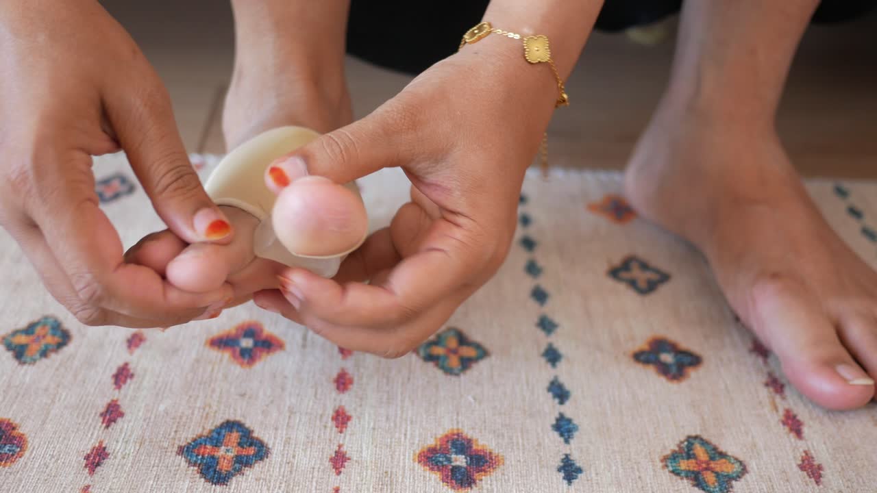 Woman Applying Bunion Bandage at Home