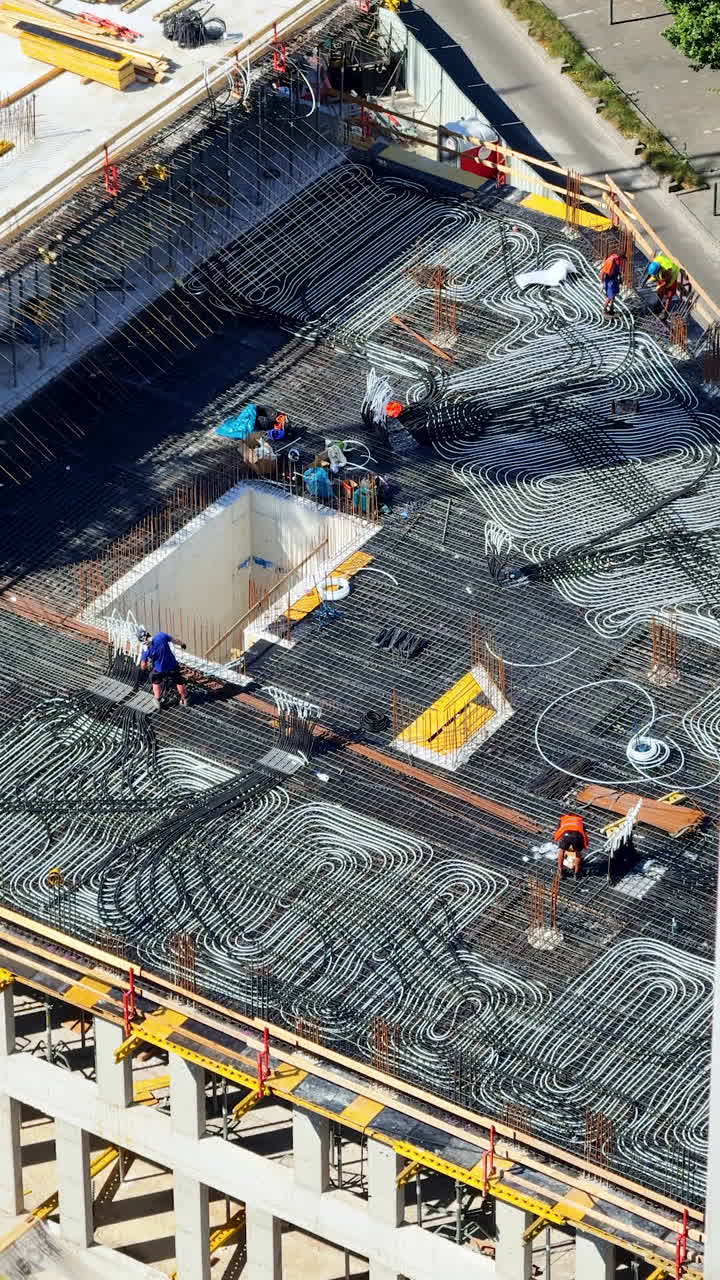 High-rise building construction. Workers are constructing a high-rise building, laying rebar on the concrete roof with various tools and equipment