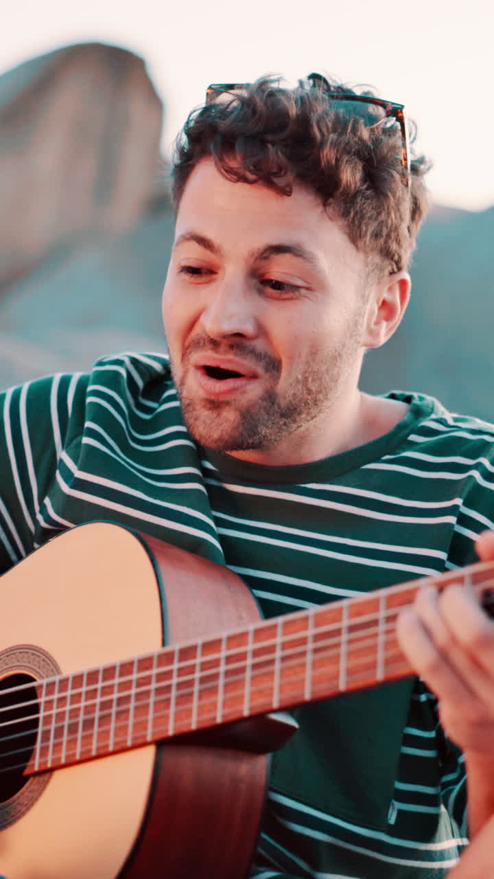 Joven feliz tocando guitarra acústica y cantando al aire libre