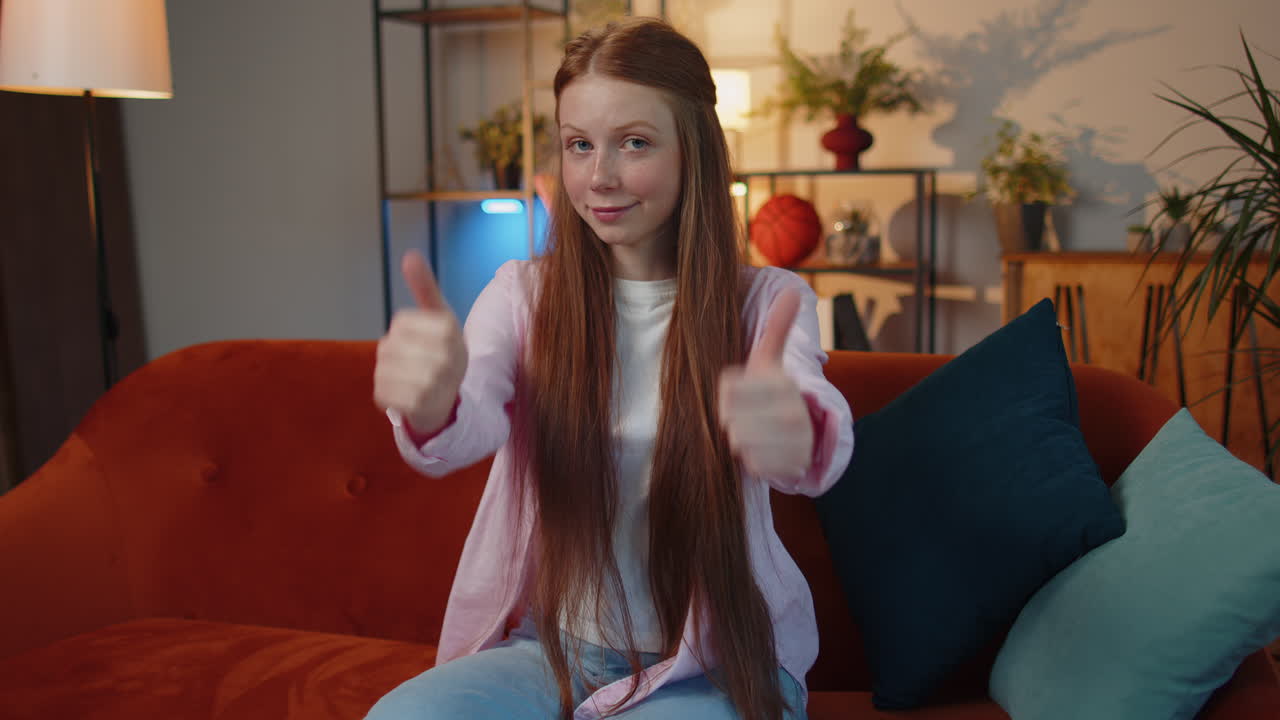 행복한 젊은 십대 아이 소녀 아이는 긍정적 인 표시처럼 엄지손가락을 보여주는 카메라에 승인적으로보고