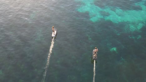 aerial shot of people surfing with efoil electric boards in the ocean near cala escondida in ibiza, spain during sunset