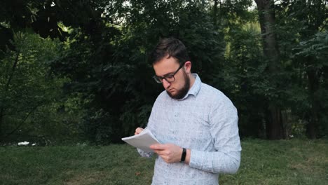 Man-with-glasses-makes-notes-in-a-notebook