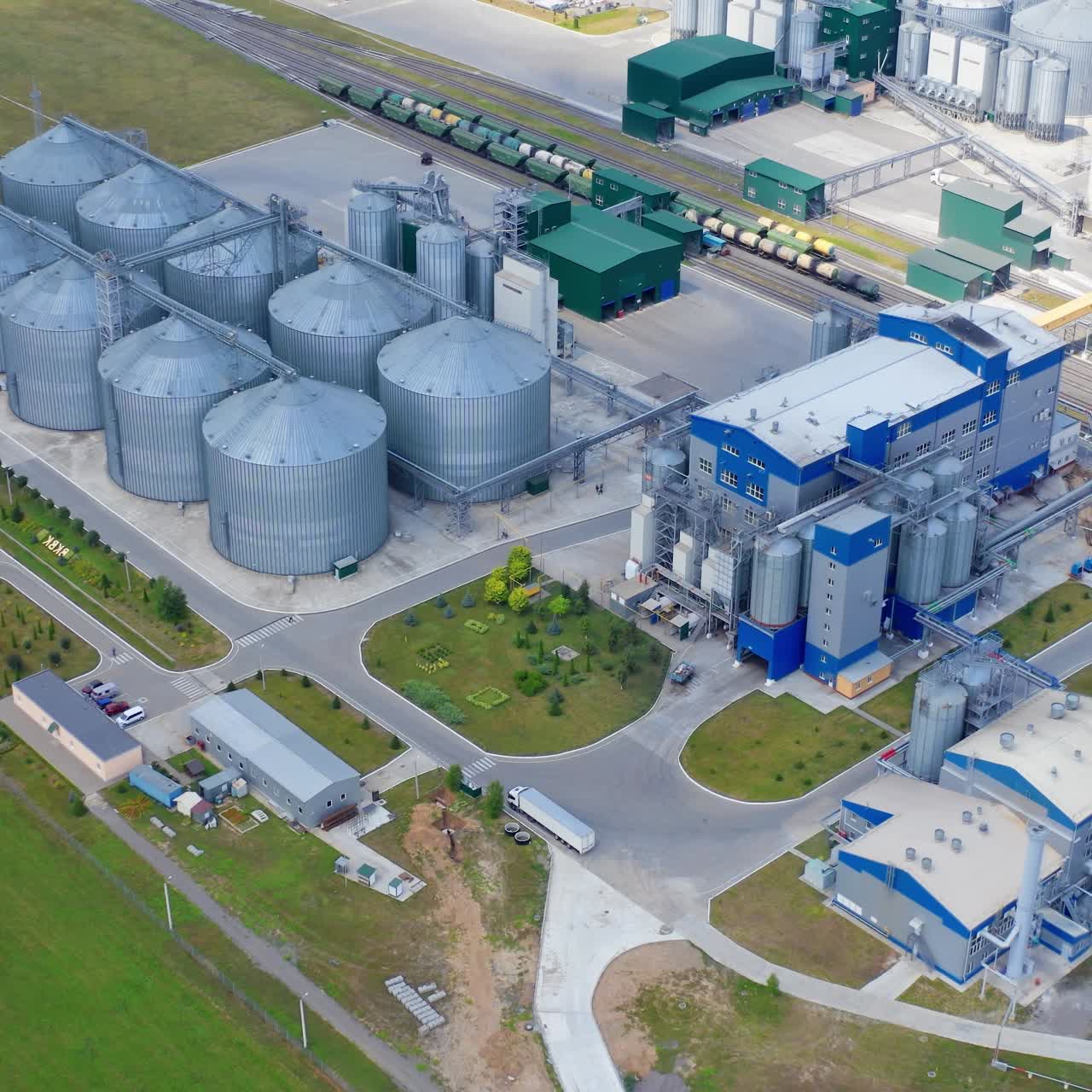 Modern factory at sunlight. Grain drying complex with metal terminals for keeping crop. New granary on field. View from the air