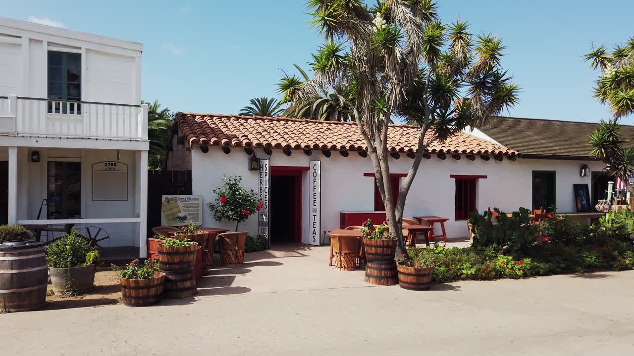 Casa bianca con tetto in argilla, palme e piante di fronte al negozio di tè e caffè San Diego House nella Old Town