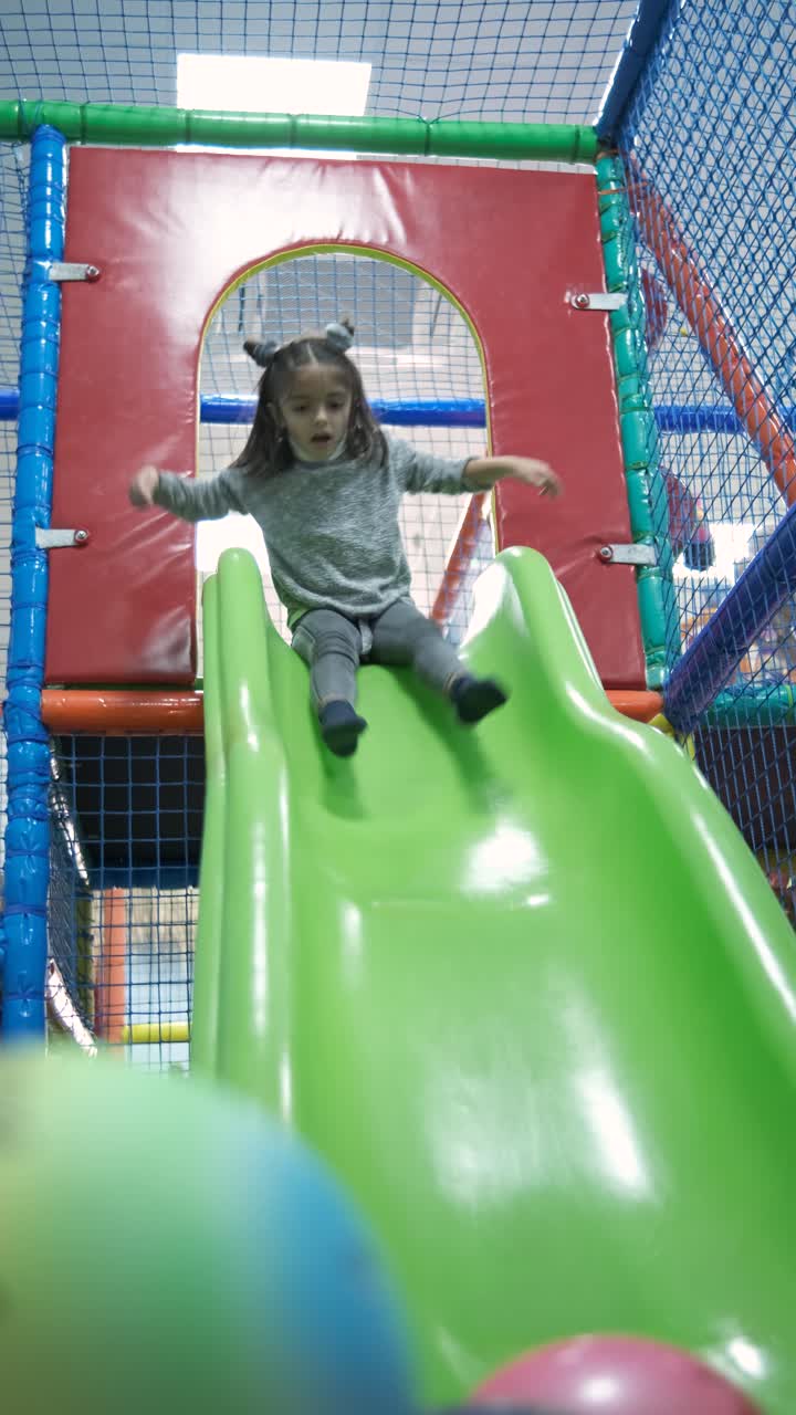 Little girl riding on slide in entertainment center