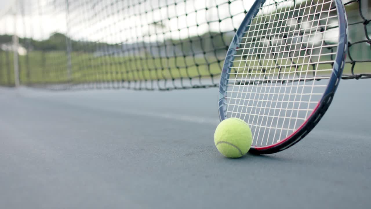 Close up of tennis racket and ball against net at outdoor tennis court, slow motion