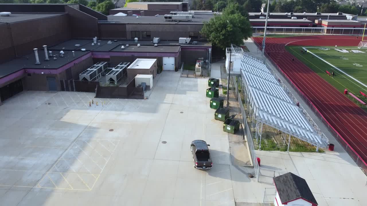A truck drives through a high school parking lot.