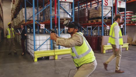 Male-warehouse-worker-using-VR-headset-and-controller-in-loading-bay-4k