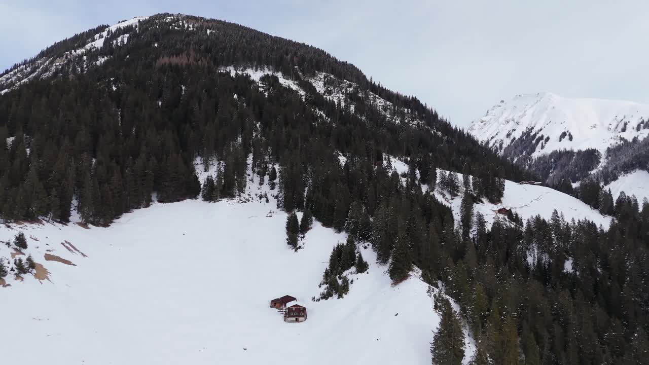 Tranquillo e incantevole paesaggio montano coperto di neve. Casetta in legno sul versante della montagna in Svizzera. Ripresa aerea in orbita