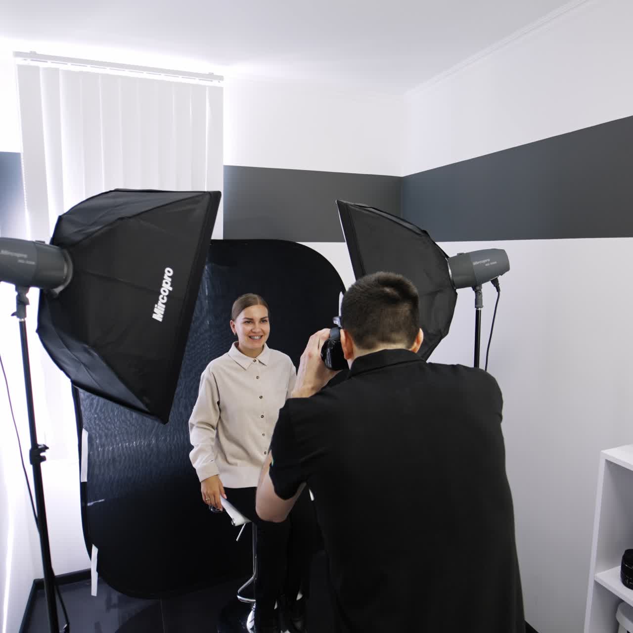 Female patient of orthodontist sitting in a chair and smiling. Medic is taking a shot of a cured teeth and braces