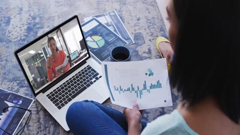 African-american-woman-holding-a-document-having-a-video-call-with-female-colleague-on-laptop