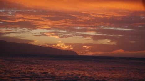 a stunning sunset over oahu hawaii north shore kaena point in orange and purple with rolling waves