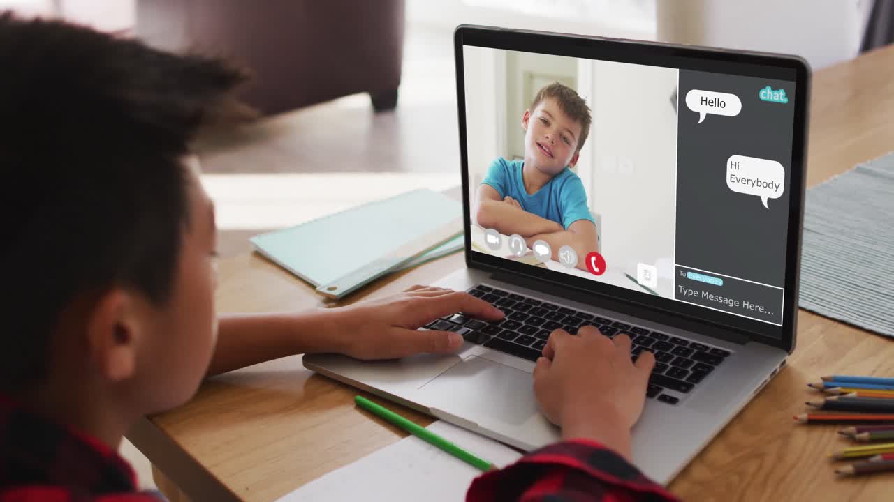 Schoolboy using laptop for online lesson at home, with school friend and web chat on screen