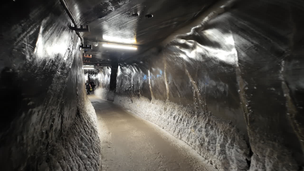 Turda, Romania - July 20, 2025: A narrow, illuminated tunnel inside the Turda Salt Mine with directional signage for visitors. Translation: "Direction signs and location names"