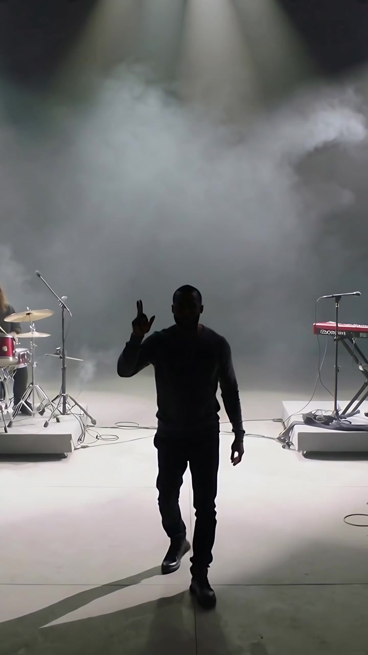 Vertical video: Walking man heeding light cue pointing stopping on stage in sweater with drums keys