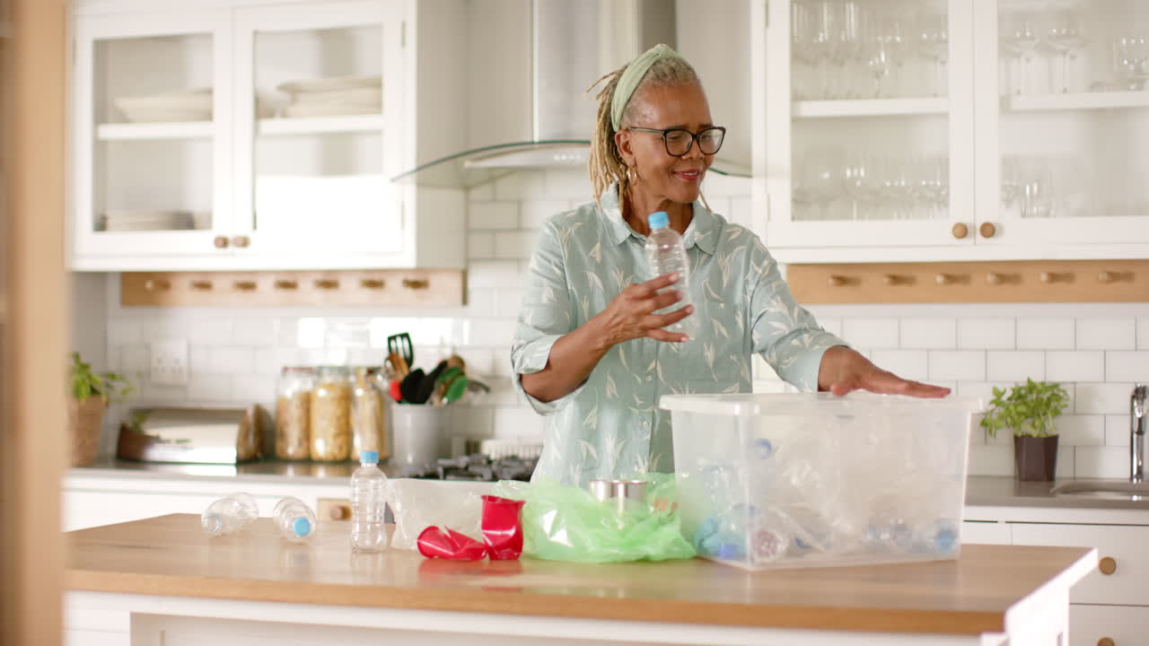 A senior African American woman sorting recycling in kitchen
