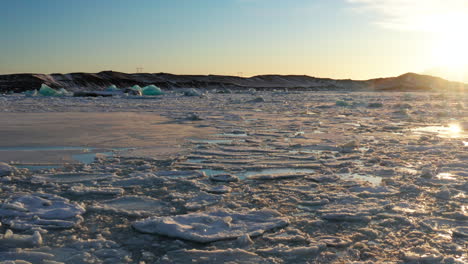 jökulsárlón glacier lagoon iceland in winter, flying over vast melted glacial water surface and floating frozen ice blocks icebergs, tourist destination in cold weather