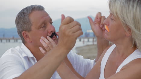 couple sticking moustaches to each other faces