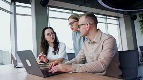 office team looking through the information on laptop. people talk, discuss, smile and suggest ideas.