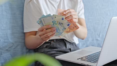 person at laptop, counting savings and paying bills online, stable closeup