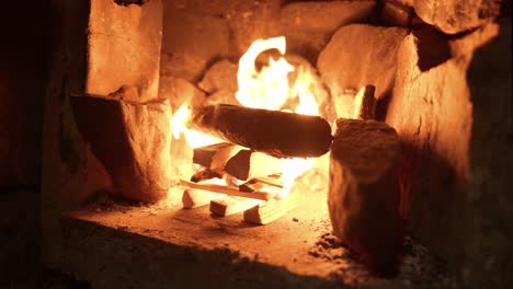 a freshly lit log fire gives out an orange glow and wooden kindling burns