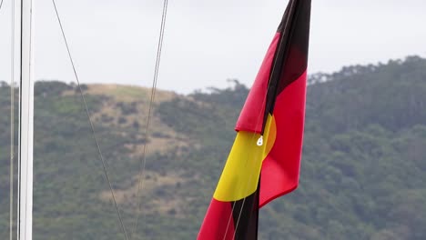 the aboriginal flag waves against a hilly backdrop on a cloudy day, captured in a series of dynamic frames