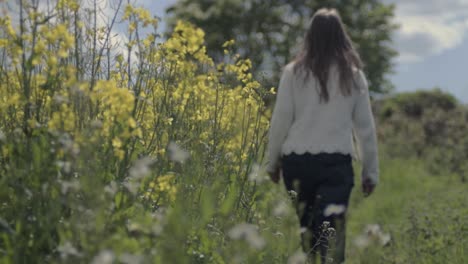 carefree woman walking through field of rapeseed in countryside landscape