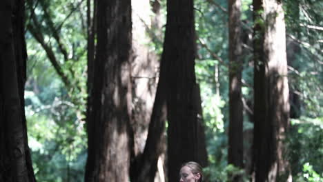 una mujer hace ejercicios de yoga en una alfombra en el bosque
