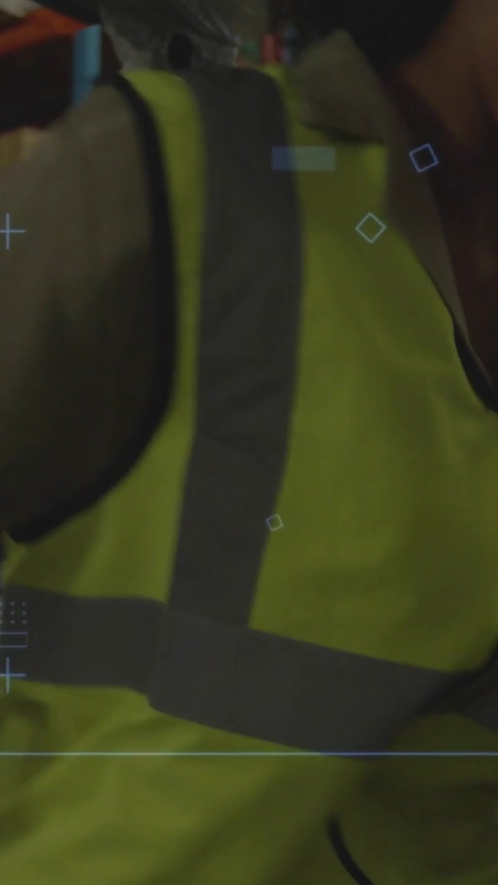 Vídeo vertical: Inspetor de armazém entrando no corredor, usando tablet, escaneando prateleiras e atualizando o estoque.