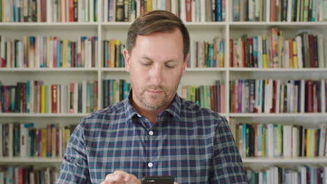 portrait-of-young-man-student-using-smart-phone-bookshelf-library-university