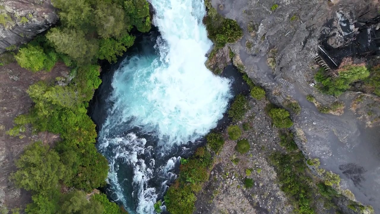 Riprese aeree dall'alto del fiume Truful Truful che scorre attraverso una stretta gola circondata da una fitta foresta verde e roccia lavica vulcanica scura