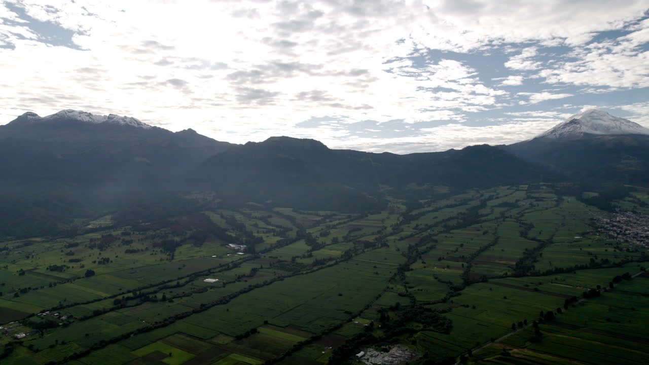 toma de dron hacia atrás que muestra la cima nevada de los volcanes popocatepetl e iztaccihutal en la ciudad de méxico y los frondosos bosques que la rodean