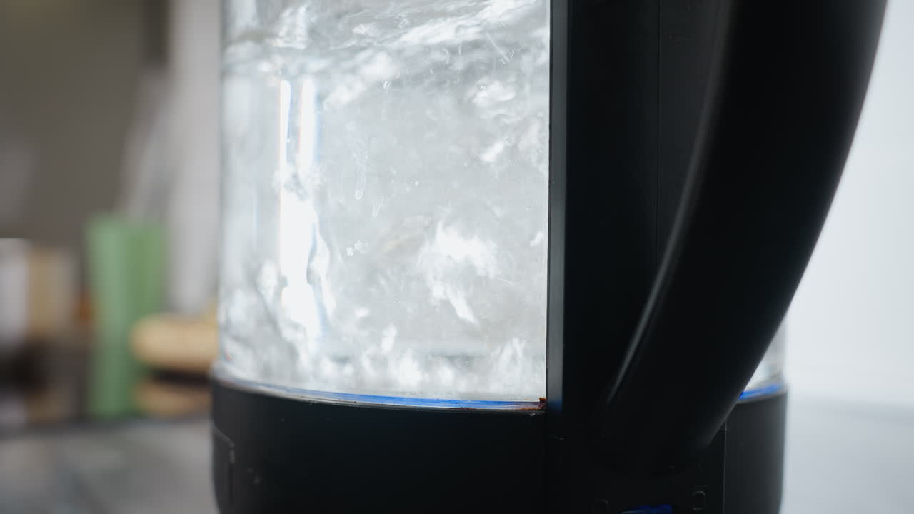 투명한 항아리에서 빠르게 는 는 물의 클로즈업, 빠른 가열 과정, 증기 및 응축을 강조하고, 흐릿한 배경으로 유리 위에 볼 수 있습니다.