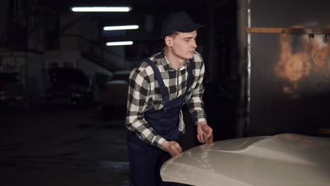 car repair technician opening the hood of the car in his workshop.