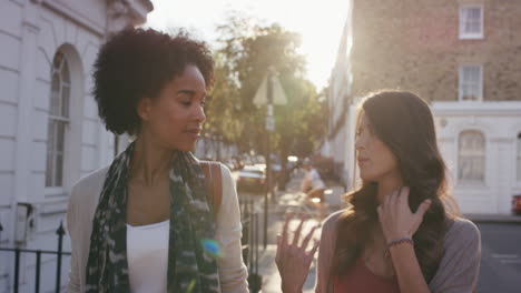 Two-beautiful-friends-walking-down-city-streets-having-fun-conversation-catching-up