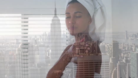 Animation-of-biracial-woman-wearing-towel-on-head-over-cityscape